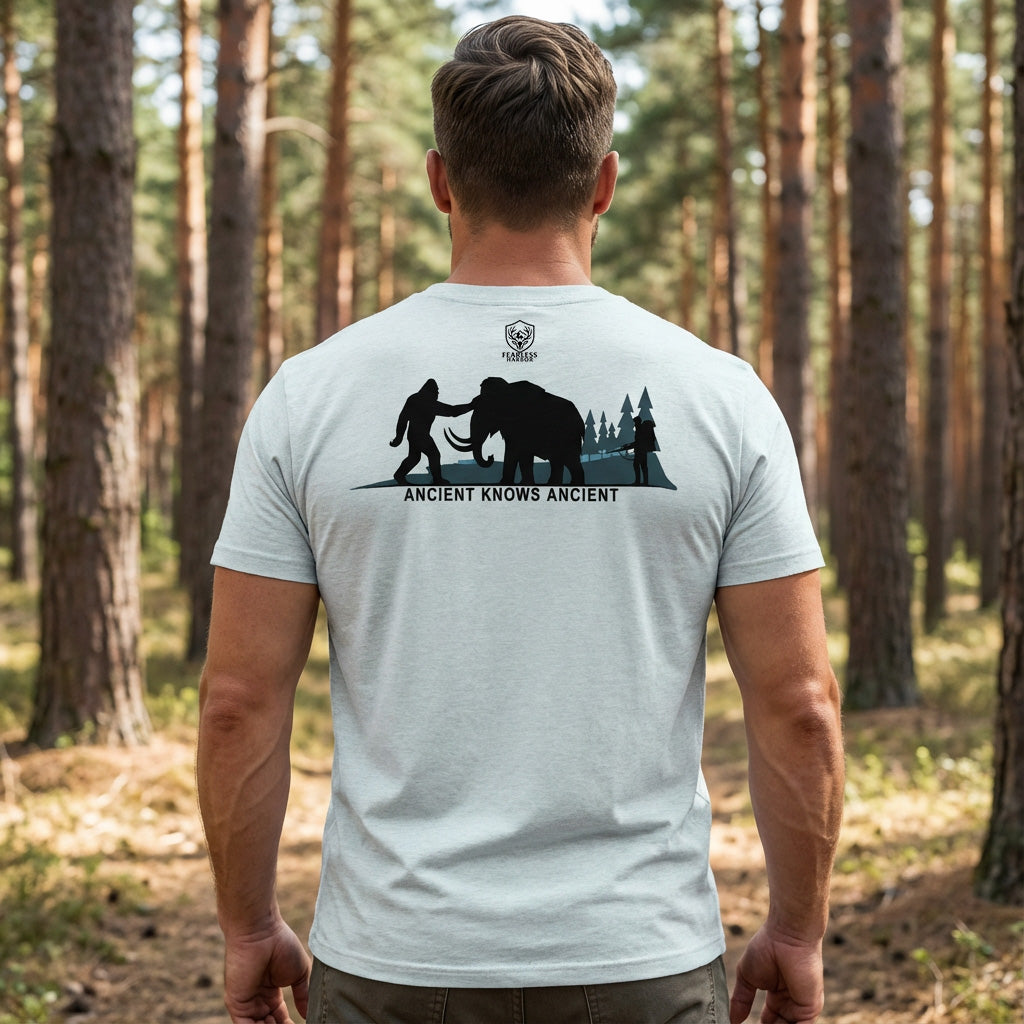 Back view of hunter wearing the Heather Prism Ice Blue Ancient Knows Ancient tee outdoors in wooded terrain